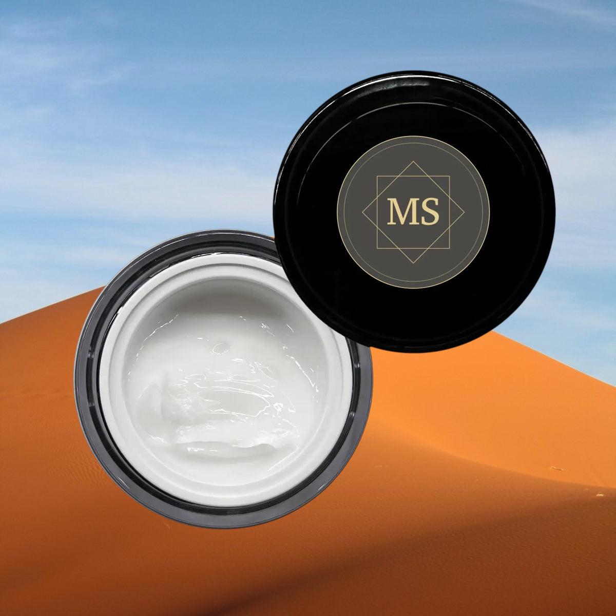 Maison Sultanat Kohl's Gaze eye contour cream in an open black jar against desert dunes